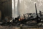 A house on N. Victor St. and W. Lyons Ave. burned by a wildfire smolders on Aug. 2, 2026, in Spokane, Wash. 