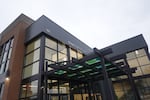 A two-story brick building is fronted by a modern-looking steel and glass facade.