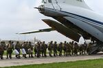 People in camouflage military uniforms line up to board a plane.
