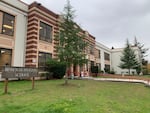 The exterior of a brick and stone school building with a grassy lawn out front.