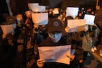 Protesters hold up blank sheets of paper and chant slogans as they march to protest strict anti-virus measures in Beijing on Nov. 27, 2022. Thousands of people demonstrated across China, waving sheets of white paper to represent the country's strict censorship.