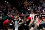 A person wearing the basketball jersey number zero zero is surrounded by cheering fans.