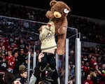 A child is lifted up to toss a teddy over the barrier and onto the ice in a decades-long tradition at a Portland Winterhawks game, Dec. 10, 2022.