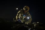 FILE — Oleksiy Yukov examines the body of a Russian soldier he collected on the frontline in the Sloviansk region, Ukraine, Tuesday, Oct. 24, 2023.