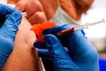 A pharmacist injects a patient with a booster dosage of the Moderna COVID-19 vaccine.