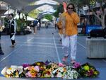 A woman brings flowers to an impromptu memorial at Bondi Junction in Sydney, Sunday, April 14, 2024, after several people were stabbed to death at a shopping center Saturday.