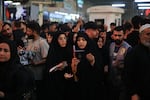 Two pilgrims recite prayers amid crowds in Karbala during the Arbaeen commemoration.