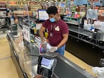 A checkout clerk works behind a plexiglass divider at the ShopRite supermarket in Uniondale, N.Y., at the start of the coronavirus pandemic.