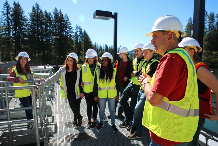 Robin Cody and students from the Clackamas Web Academy stand on a platform just above the Clackamas river.