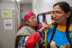 Cindy Yallup, left, ties the ribbons of daughter Norma Patrick’s wing dress as the women prepare for winter solstice at the longhouse in Mission, Ore., on Dec. 21. They were visiting from the Yakama reservation and said they enjoyed seeing family and hearing the singing and the laughter in the kitchen.