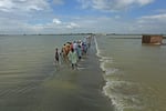 Stranded people wade through a flooded area after heavy monsoon rainfall in Rajanpur district of Punjab province on Aug. 25.