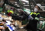 California is enacting a new ban of single-use plastic bags at grocery stores and other retailers, after an earlier ban was blamed for making the waste problem worse. Here, a worker pulls a plastic bag from a conveyor belt as she sorts through materials at a recycling center in San Francisco.