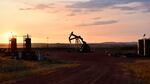 An oil well works at sunrise.