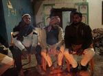 Men sit around a fire outside a crumbling mosque in Ayodhya.