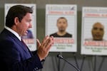 Florida Gov. Ron DeSantis speaks during a press conference in front of posters of people that law enforcement arrested, held at the ICE Enforcement and Removal Operations office on May 1, 2025 in Miramar, Fla. Florida has issued its own financial incentives to encourage more local police cooperation with ICE.
