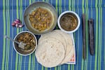 Clockwise from the biggest bowl: • Chicken curry with yesur, a powdered spice mix that contains red chillies, coconut and eight other spices. • Shepu and chuka, a mix of two green vegetables. • Jowar bhakri, a flatbread made of millets. • This bowl has two separate mixed veggies. The one on top is methi with moong dal (fenugreek and lentils), the one at the bottom is paat with toor dal (spring onion and lentils) all recipes from The Dalit Kitchens of Marathwada by Shahu Patole, in Khamgaon, India on November 11, 2024. Maya Levin for NPR
