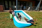 Jalen Askari, 7, right, plugs his nose as he falls into the pool he is playing in with his siblings, from left, Amari, 5, Bella, 2, and DJ, 10, in Portland, Ore., Tuesday, July 26, 2022. The temperature hit 102 that day, in the midst of the city's record streak of 95-plus degree days.