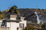 A helicopter drops water near evacuated homes in Laguna Beach, Calif. New homes in high risk zones in the state must use fire-resistant materials in construction.