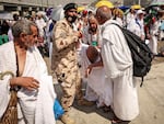 A man affected by the scorching heat is helped by another Muslim pilgrim and a police officer during the Hajj pilgrimage in Mina on June 16.