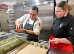 Chef Nephi Craig, left, showing high school senior Zoey Koehler a culinary technique on Nov. 22, 2025. Eleven students from Siletz Valley School were paired up with Indigenous chef-mentors for a First Foods dinner at at The Allison Inn & Spa in Newberg, Ore.