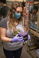 Portland State University student Catie Spivey holds a model of OreSat0 in 2021. The group's second satellite is scheduled for launch in July 2024.