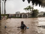 Maximiliano Encarnacion uses a broom to push through floodwaters from Hurricane Maria in San Juan, Puerto Rico, in 2017. The initial official death toll from the storm was in the dozens, but subsequent epidemiological analyses suggested that thousands of additional deaths had gone uncounted.