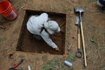 A field worker carefully excavates a pit near the spot where an Oregon landowner discovered a cache of 14 obsidian tools.