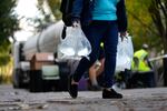 A person carries bags of fresh water after filling up from a tanker at a distribution site in the aftermath of Hurricane Helene on Wednesday in Asheville, N.C. 