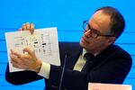 FILE - In this Feb. 9, 2021, file photo, Peter Ben Embarek of the World Health Organization team holds up a chart showing pathways of transmission of the virus during a joint news conference at the end of the WHO mission in Wuhan in central China's Hubei province. A joint WHO-China study on the origins of COVID-19 says that transmission of the virus from bats to humans through another animal is the most likely scenario and that a lab leak is "extremely unlikely," according to a draft copy obtained by The Associated Press.