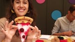A woman holds a slice of pizza made of felt.
