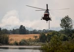 A firefighting helicopter lowers to refill water from a pond west of Friend, Ore., to fight the Grasshopper Fire during a tour of the wildfire on Aug 3, 2026.