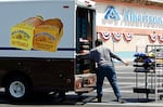 A bread salesman unloads a box truck with loaves of bread in front of an Albertsons grocery store.