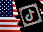 The social media application logo, TikTok is displayed on the screen of an iPhone on an American flag background. With the TikTok CEO set to testify on Capitol Hill on Thursday, influencers and lobbyists are pressing the government not to ban the app.