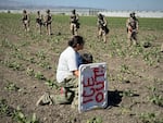 A demonstrator kneels in front of federal agents in a farm field during an immigration raid in Camarillo, Calif., Thursday, July 10, 2025.