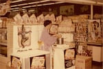 A woman dresses in traditional Japanese kimono serving Kubla Khan frozen dinner samples at a grocery store in the 1960s at an unspecified location.