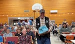 Baker County Sheriff Travis Ash carries a blue salt lick preparing to be auctioned at The Great Salt Lick contest & auction while smiling people sit behind.