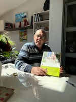 Jean-Pierre Salaün at his home in Le Drennec, France, holds a book about the town during World War II. He is incensed that the book talks of horses that were killed, but does not mention his grandfather.