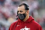 A man with a microphone and headset and facemask wears a red WSU Cougars sweat shirt