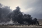A thick plume of smoke rises from an oil storage facility hit by a U.S.-Israeli strike late Saturday in Tehran, Iran, Sunday, March 8, 2026.
