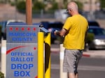 A voter places a ballot in an election voting drop box in Mesa, Ariz., on Friday.