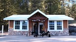 A woman, a man, and five dogs exit a small poolhouse.