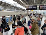 Passengers prepare to board a Shinkansen train at Kyoto Station.