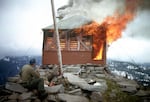 A Forest Service employee takes a lunch break as he watches the East Zigzag Mountain Lookout burn in 1965. Many lookouts were intentionally destroyed on national forests after they were no longer needed for fire detection purposes. In the 1980s, some of the surviving lookouts found a new role in outdoor recreation as overnight rentals.