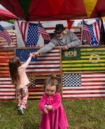 Kevin Elwess hands candy to a child at his booth. Elwess makes flag art out of wood and was one of many vendors at the event.