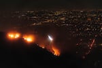 A helicopter drops water as fire burns on the Sunset Fire in the Hollywood Hills area of Los Angeles on Wednesday night.