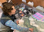 A woman points to a map on a table.