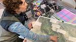 A woman points to a map on a table.
