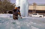 City of Richardson worker Kaleb Love breaks ice on a frozen fountain Tuesday, Feb. 16, 2021, in Richardson, Texas.  Temperatures dropped into the single digits as snow shut down air travel and grocery stores.
