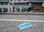 A disposable mask sits discarded in a city street.