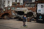 A boy rides a scooter past a display of destroyed Russian military vehicles in Mykhailivska square in central Kyiv, Ukraine on Tuesday, Oct. 22, 2024.